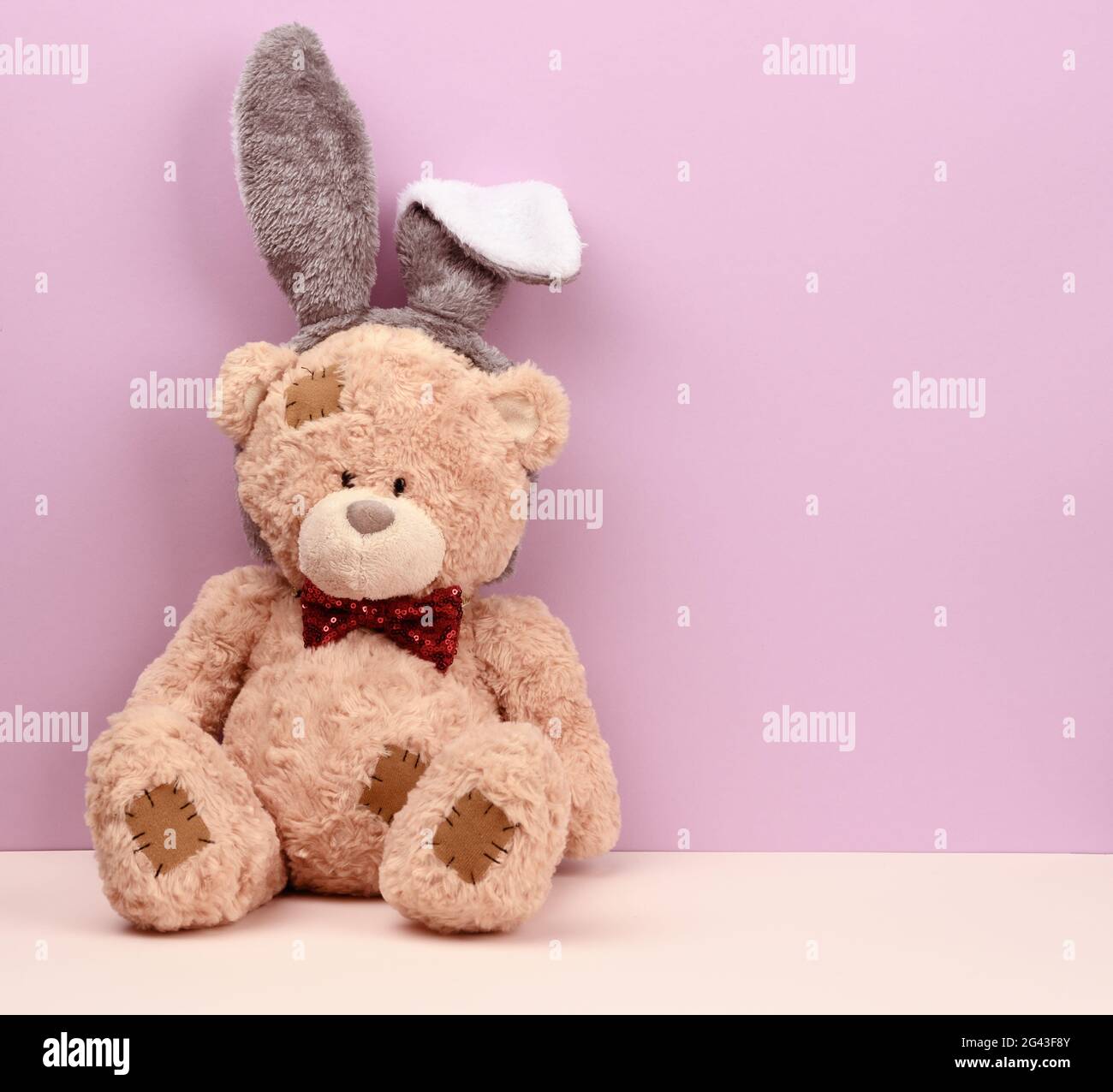 Cute brown teddy bear wearing a rabbit mask with long ears on his head