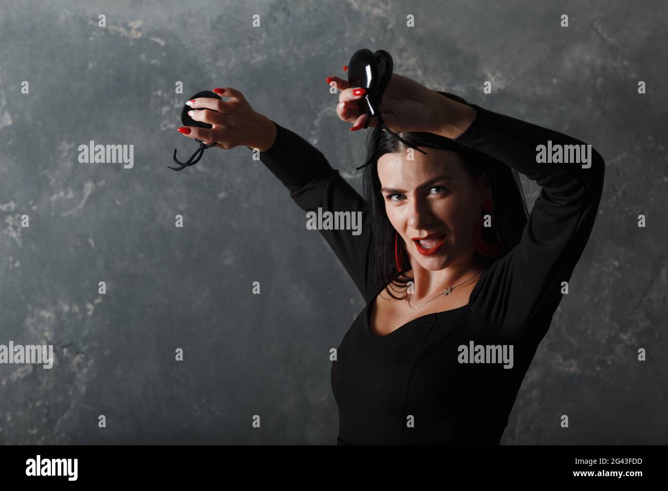 Young adult spanish woman dancing flamenco with on gray