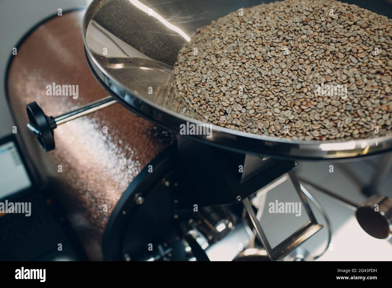 Coffee roaster machine at coffee roasting process. Young woman worker
