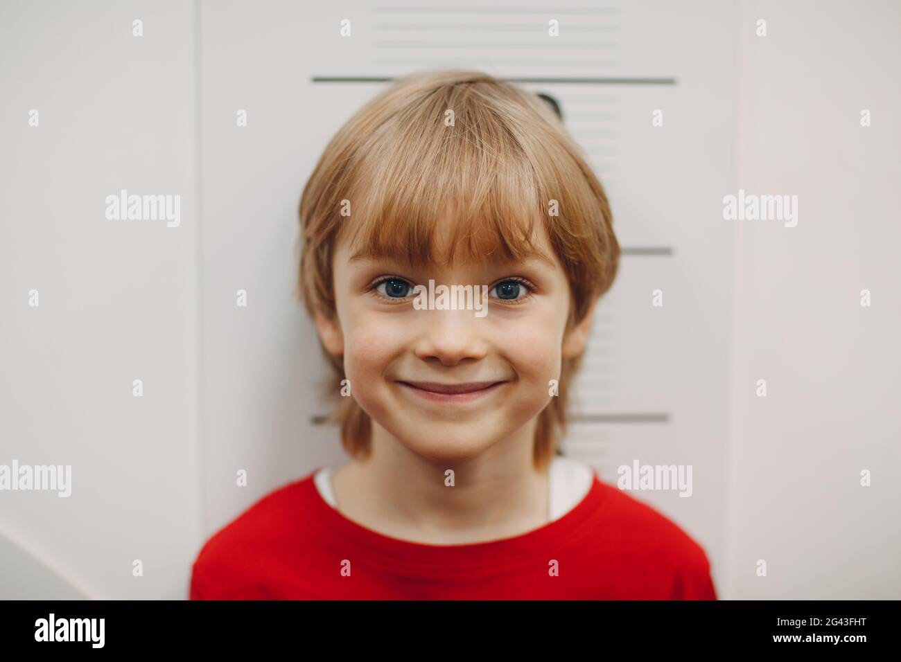 Children little boy are measured growth height at wall scale. Kid smile portrait. Stock Photo