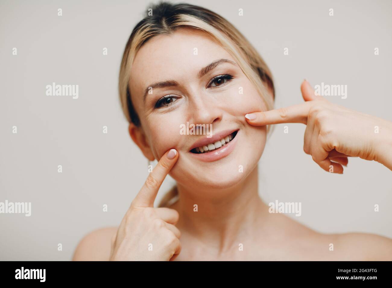 Young adult smile woman doing facial gymnastics self massage and rejuvenating exercises face building for skin and muscles lifti Stock Photo