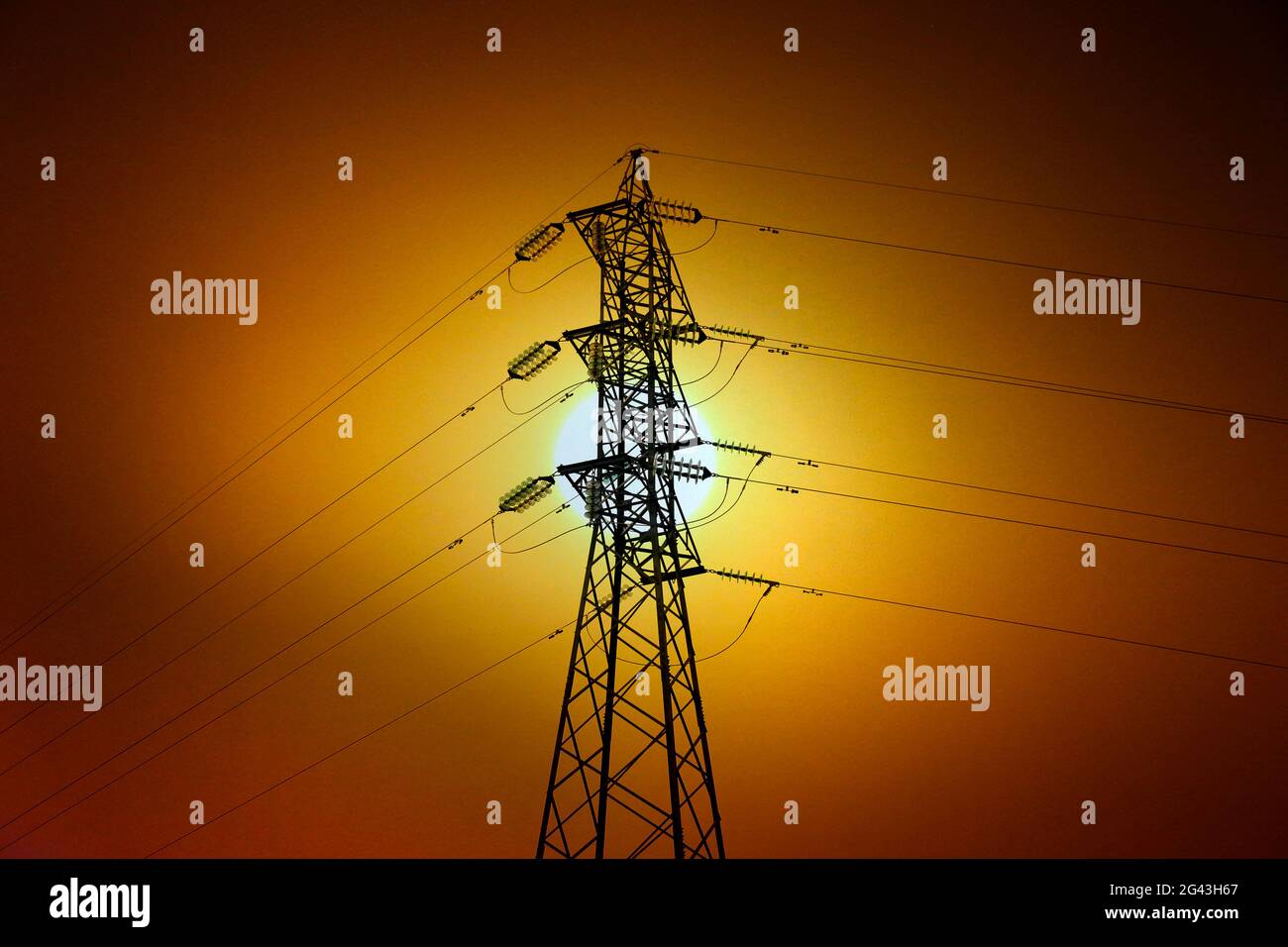Electric power transmission tower in backlight and bright sun Stock Photo