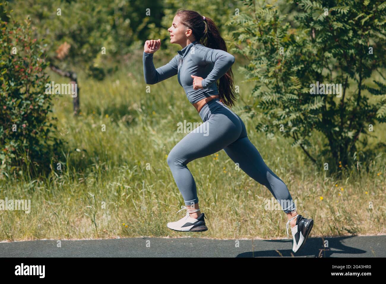 Running girl in city park. Young woman runner outdoor jogging. Side view. Stock Photo