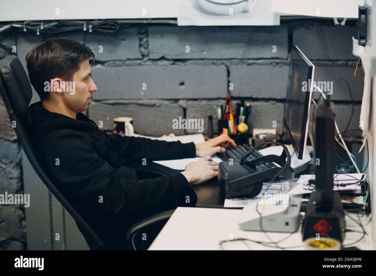 Young man programmer gamer sitting on chair with computer desktop near ...
