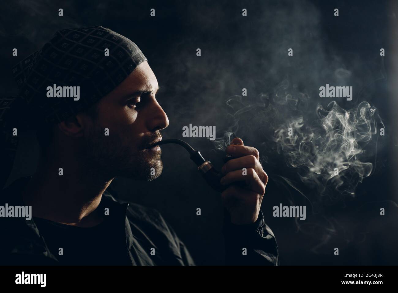 Man smoking a pipe on dark background. Back lit profile portrait Stock  Photo - Alamy