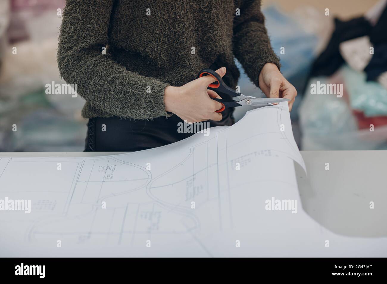 Young beautiful seamstress cutter clothing designer in a garment factory. Stock Photo