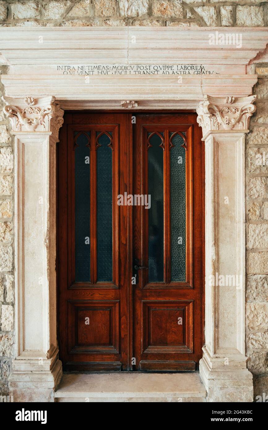 Dubrovnik, Croatia - 04 may 2016: Red wooden door in a stone capital in the Dominican Monastery in Dubrovnik, Croatia. Stock Photo