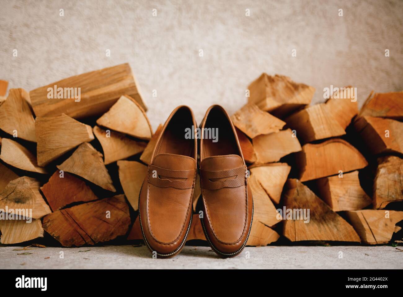 Brown men's shoes Penny loafers at the wood logs for the firebox. Stock Photo