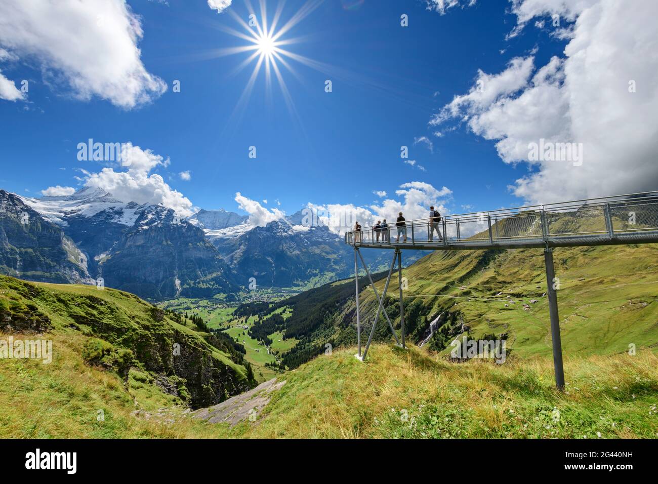 Several people stand on cliff walk with a view of Schreckhorn