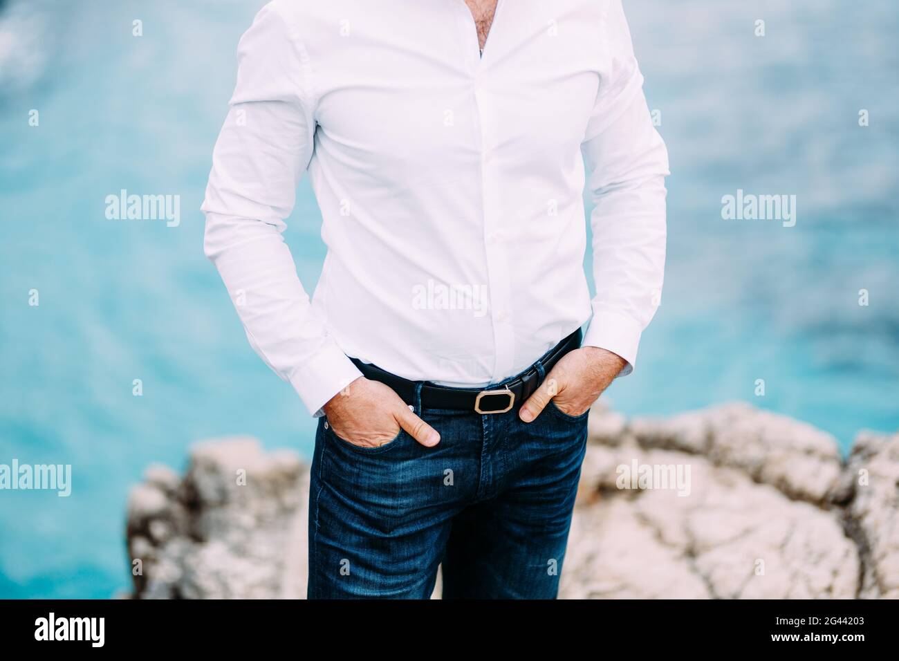 Man is standing on a rocky beach with his hands in the pockets Stock Photo