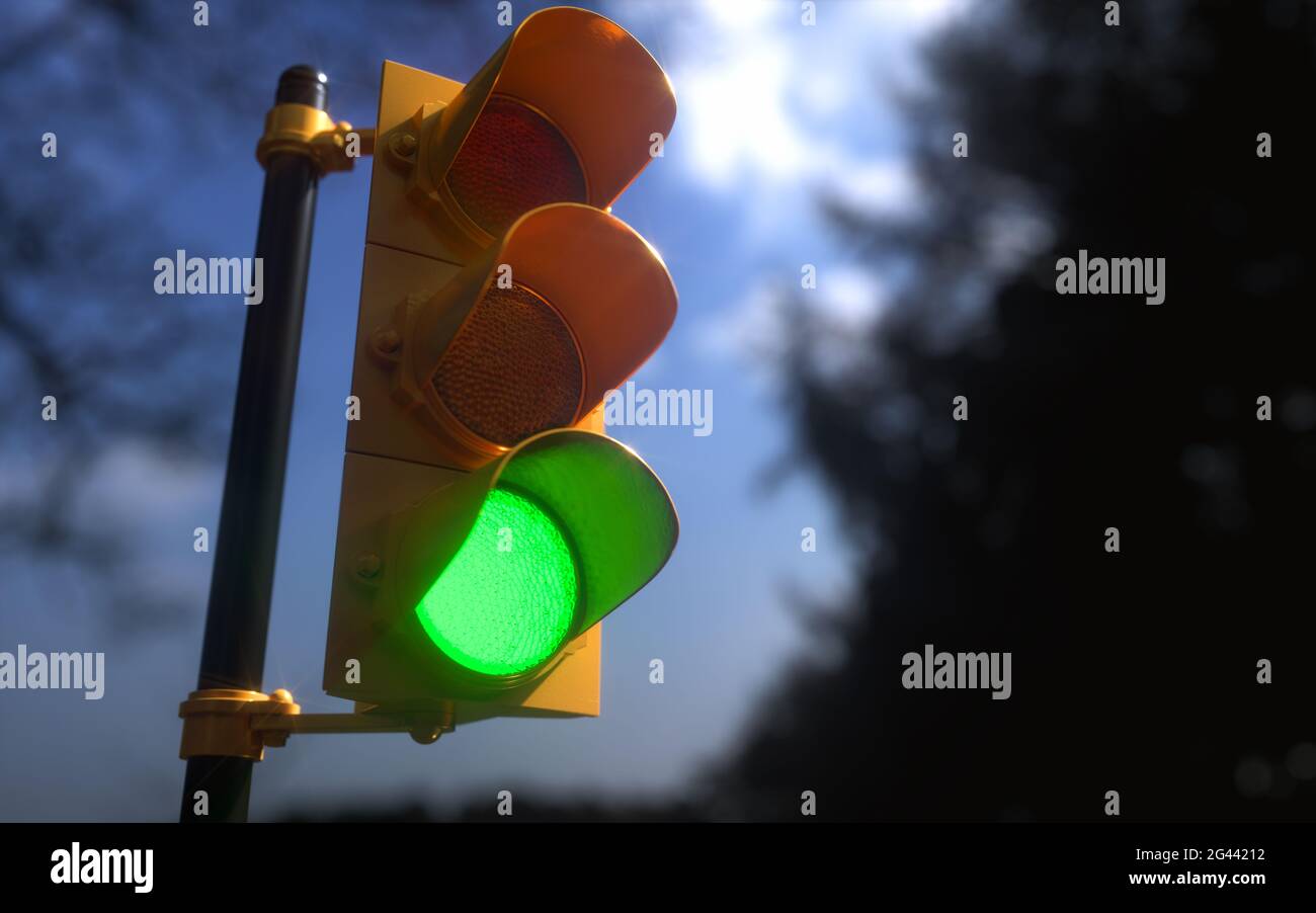 Outdoor vertical traffic light with blue sky and trees around. Traffic control concept image with shallow depth of field. Stock Photo