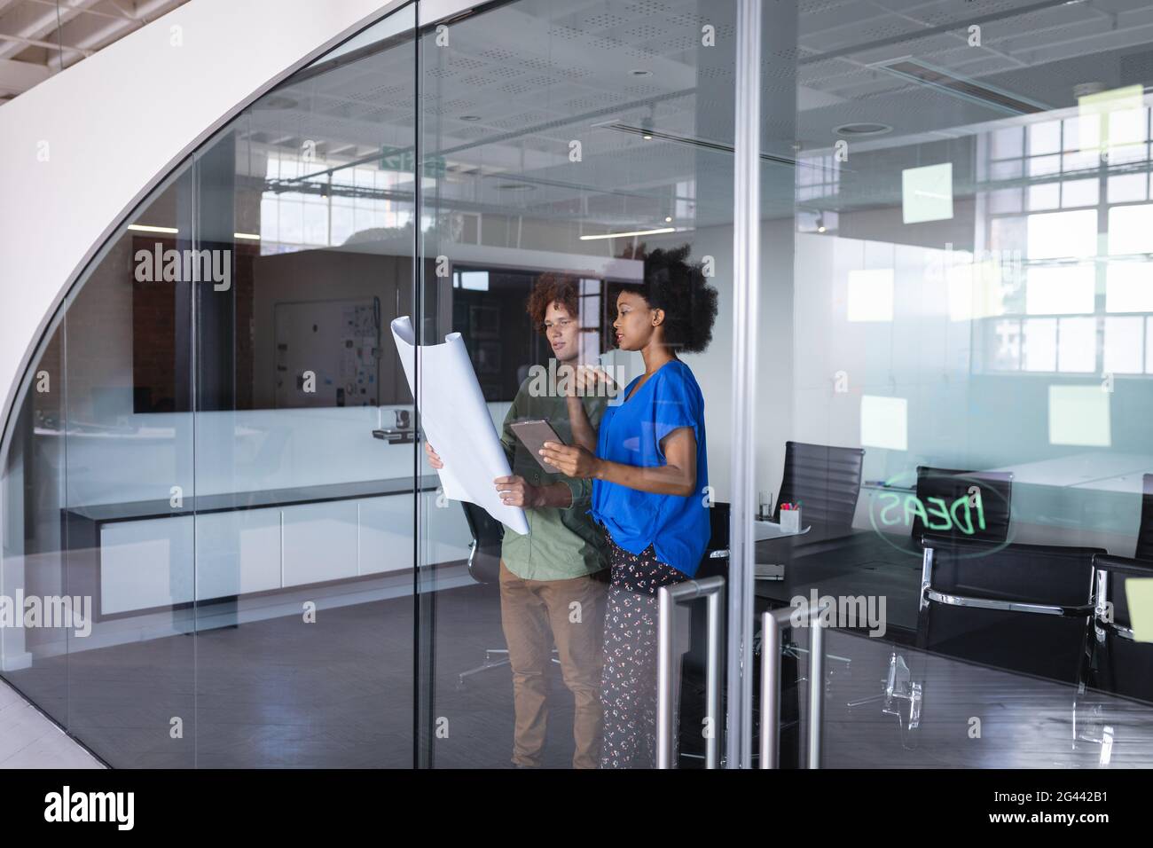 Diverse male and female colleagues in office discussing over blueprint ...