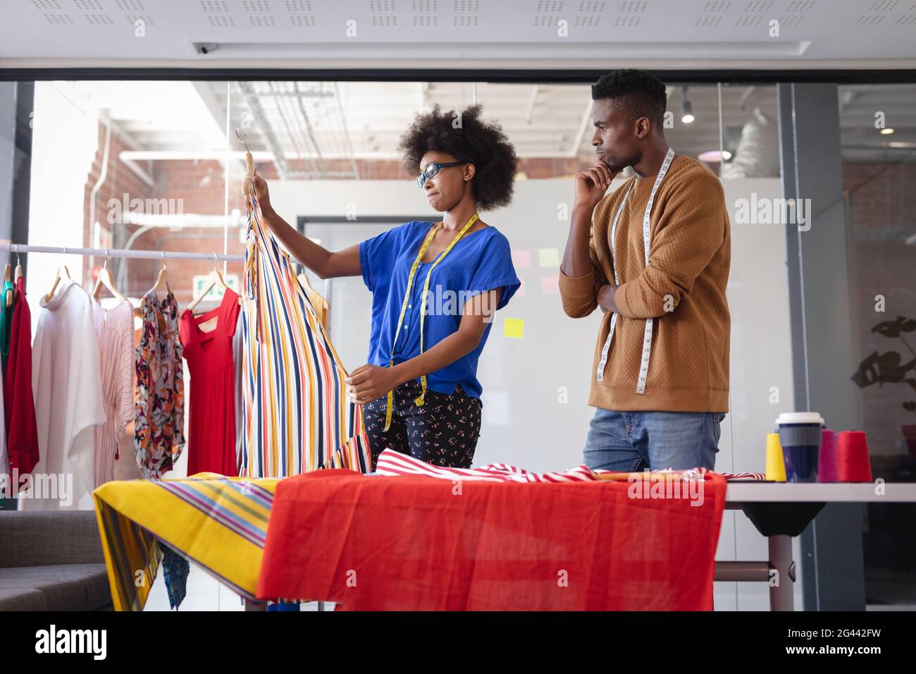 Diverse male and female fashion designers at work discussing and ...