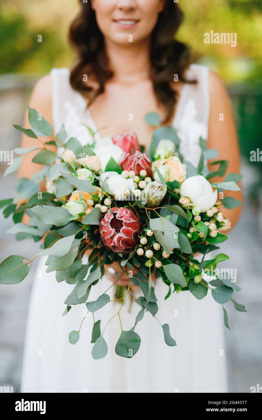 A gentle bride holds in her hands an unusual wedding bouquet of white ...