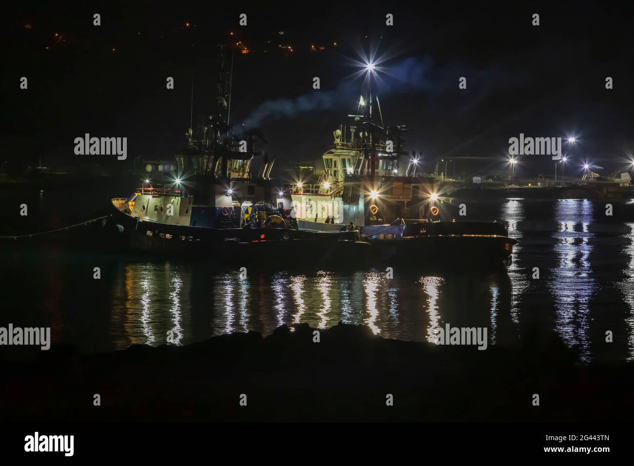 Tugboat in port at nighttime undergoing routing maintenance Stock Photo