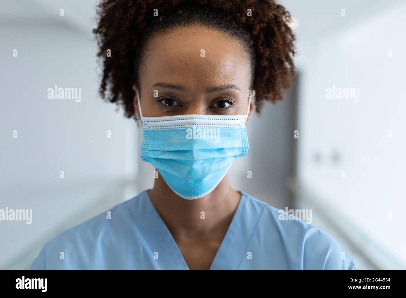 Portrait of african american female doctor wearing mask standing in ...
