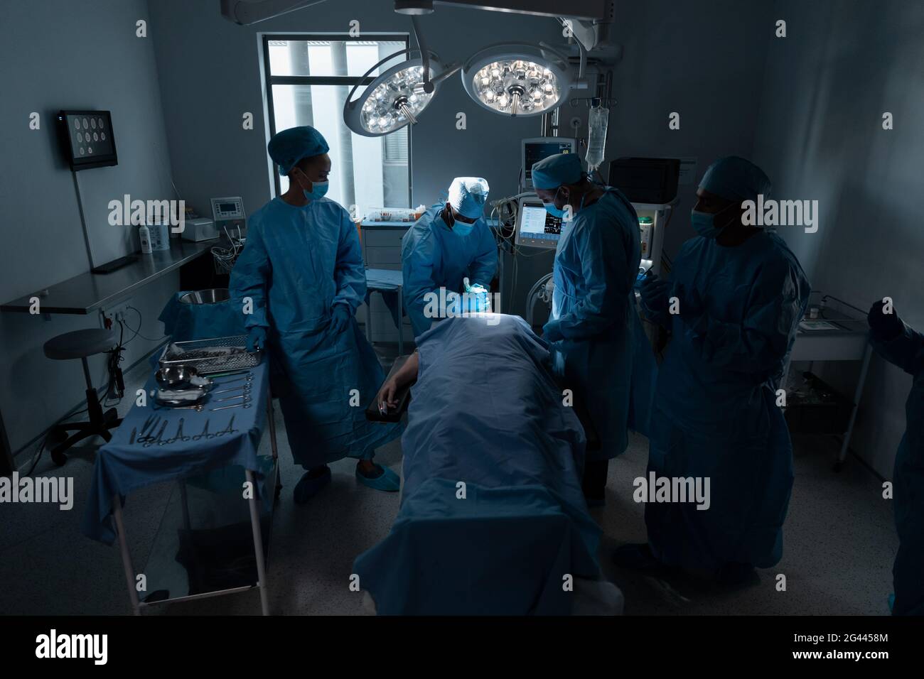 Diverse male and female doctors wearing face masks and surgical overalls in operating theatre