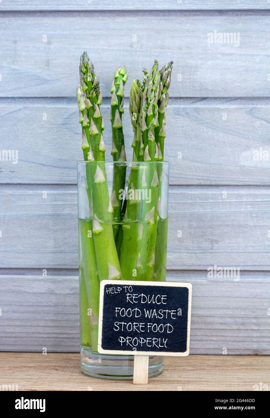 asparagus stored in water in glass to preserve it longer, help to reduce food waste, store food properly text. Good food storage to reduce home waste. Stock Photo