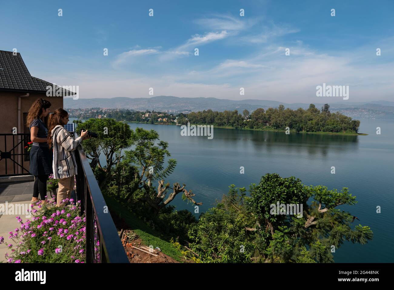 Young women overlook Lake Kivu from the terrace of the Emeraude Kivu Resort with the town of Bukavu in the Democratic Republic of the Congo in the dis Stock Photo