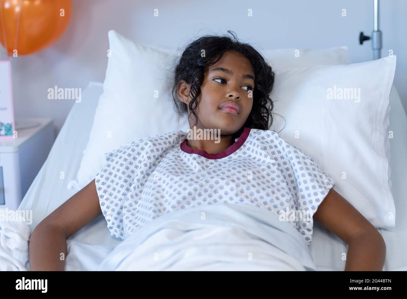 Bored sick mixed race girl lying in hospital bed looking away Stock Photo