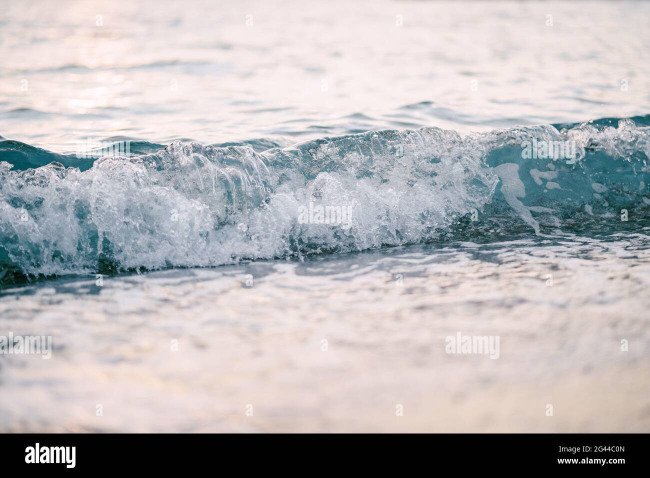 Sea waves run over one another. Close-up of a sea wave at sunset. Stock Photo
