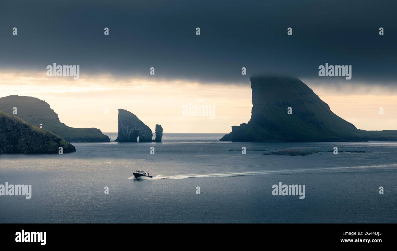 Boat in front of rock formations of Drangarnier and Tindholmur island ...