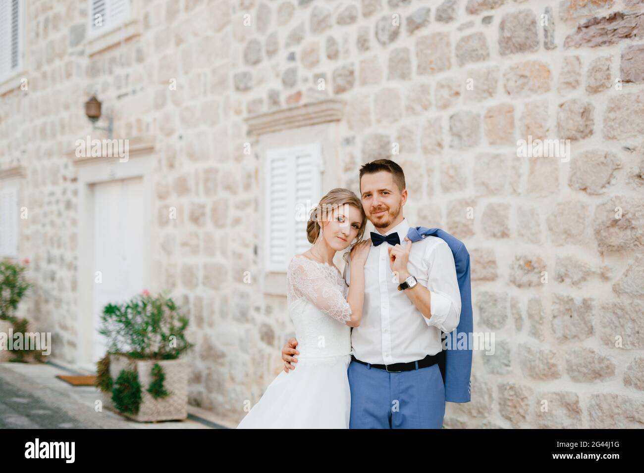 The bride and groom stand hugging near a beautiful brick house in the ...