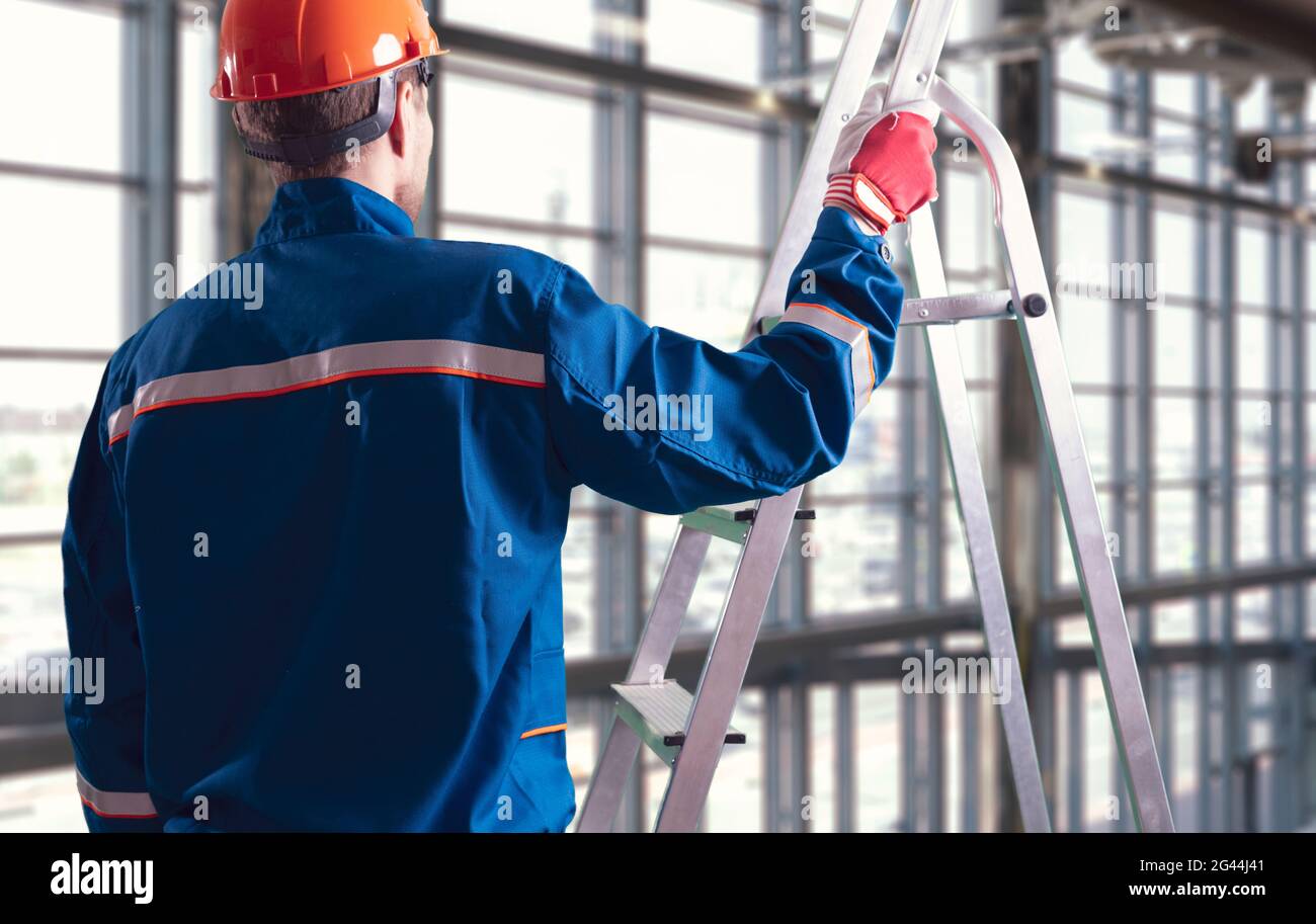 male worker on construction site holding and carrying the ladder Stock ...