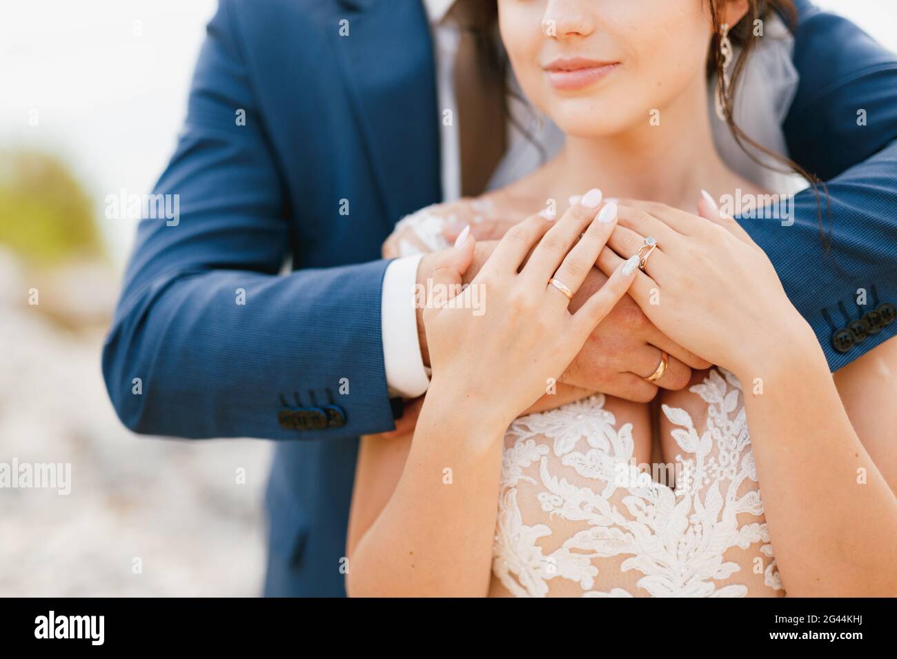 The groom gently hugs the bride by the shoulders, the bride put her hands on the groom's arms, close-up Stock Photo