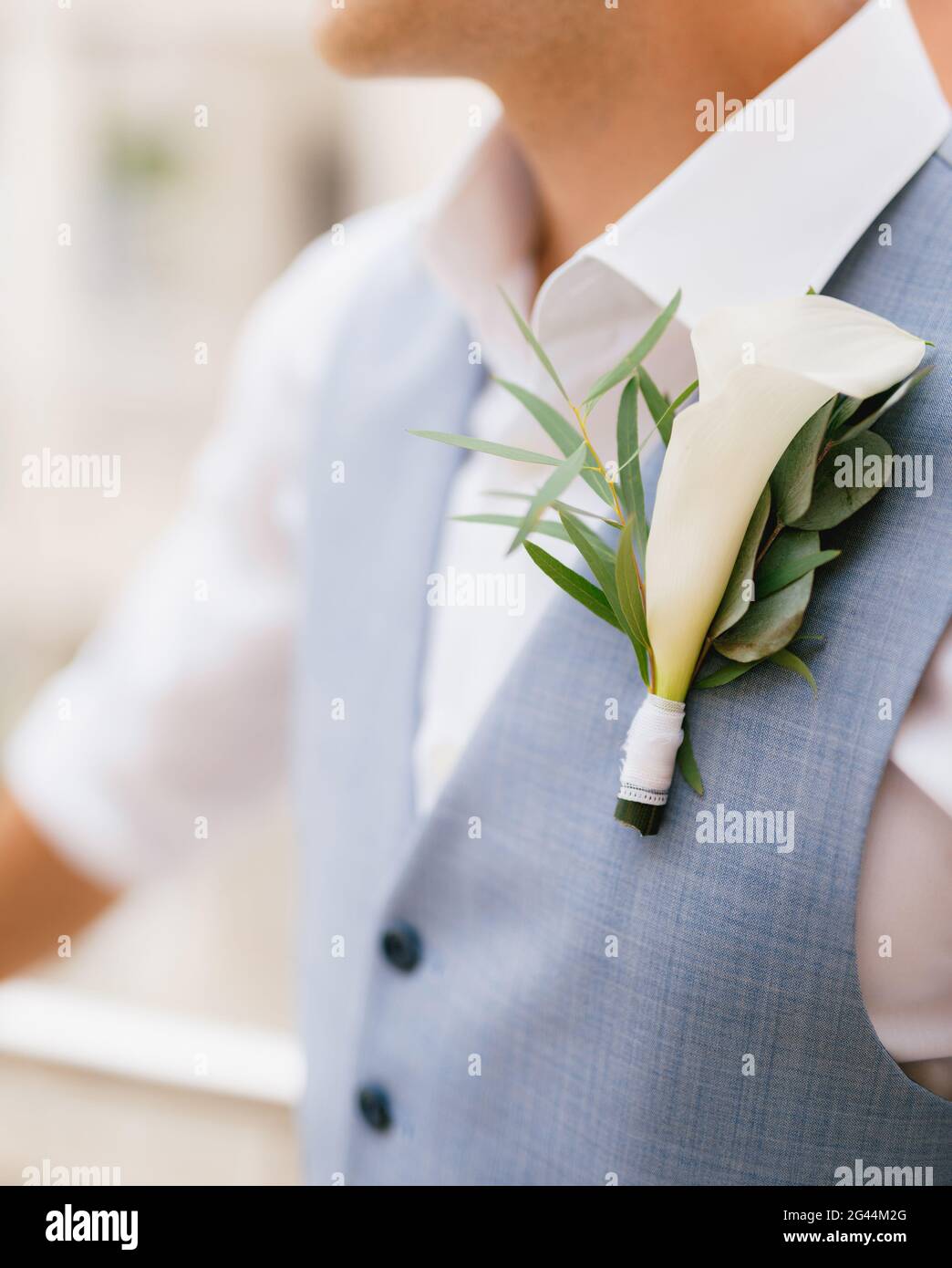 The groom in a shirt and vest with a boutonniere stands on the balcony in the morning before the wedding ceremony, close-up Stock Photo