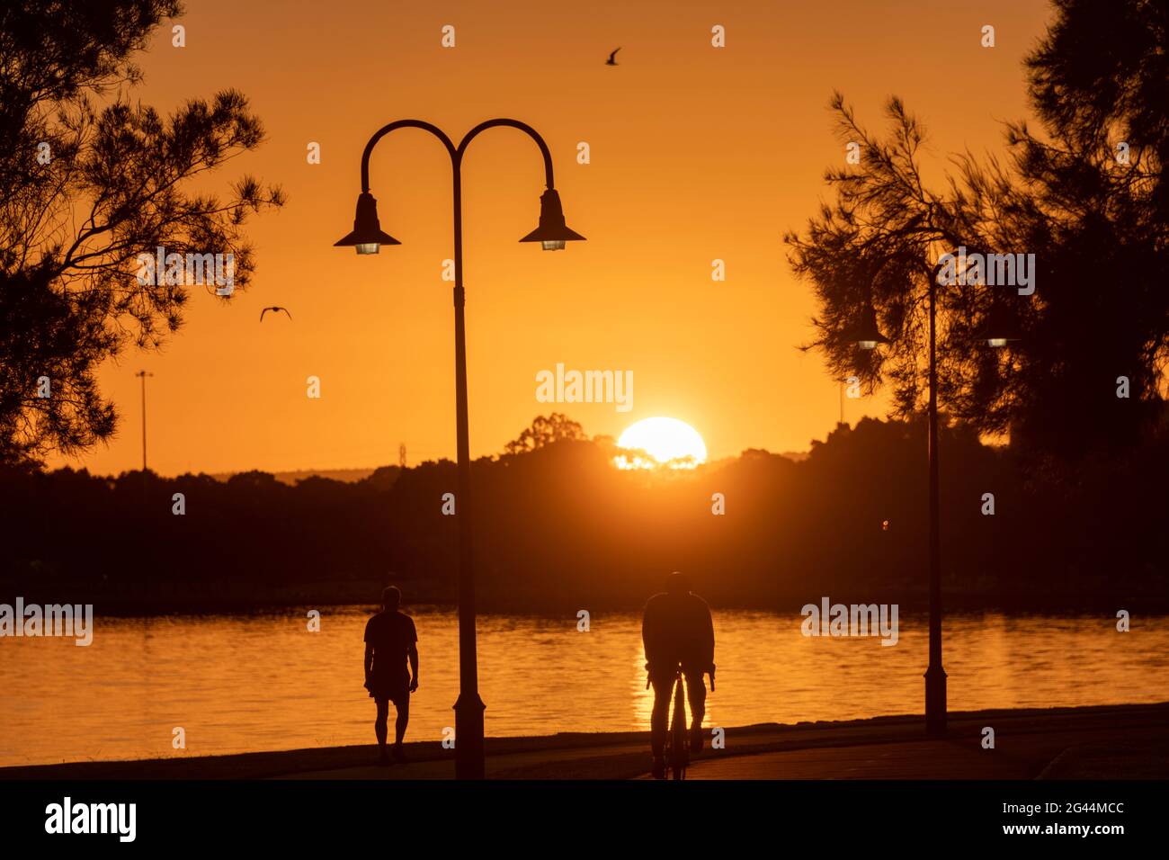 People excercising along Perth's Swan River at sunrise. Stock Photo