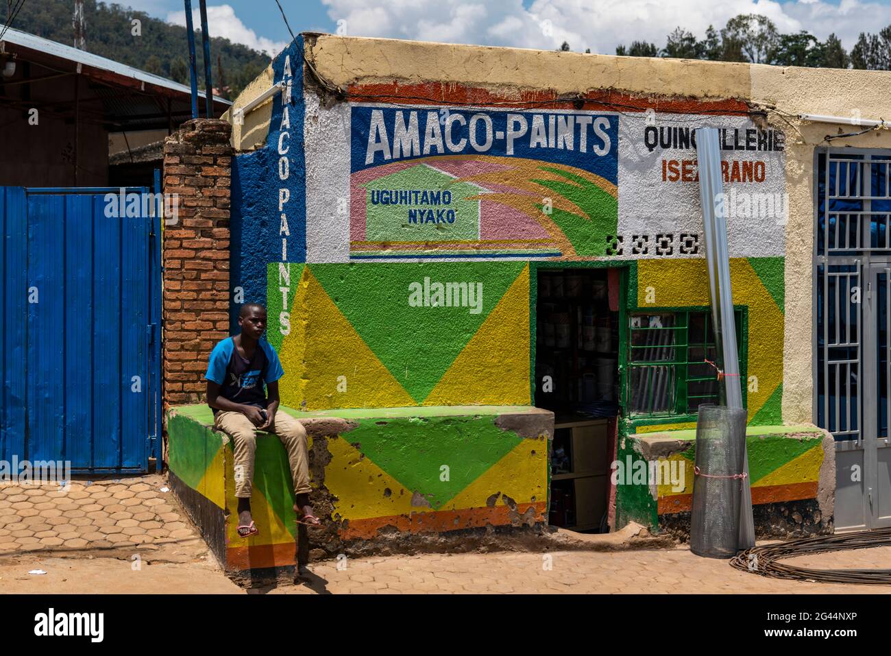Young man sitting in front of a paint shop, Kigali, Kigali Province