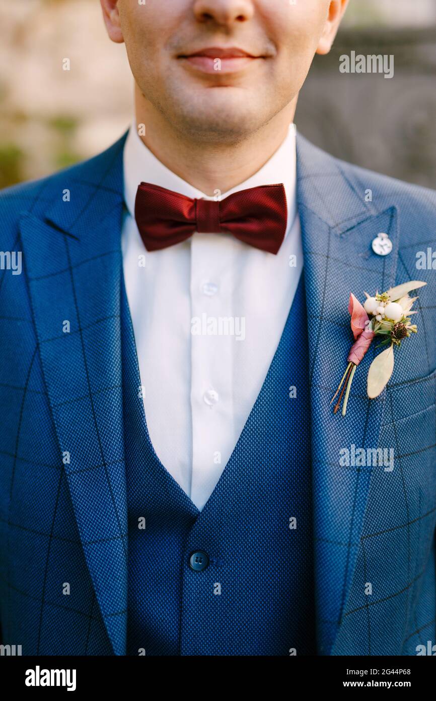 Smiling groom in blue plaid three-piece suit and white shirt with red bow-tie and boutonniere Stock Photo