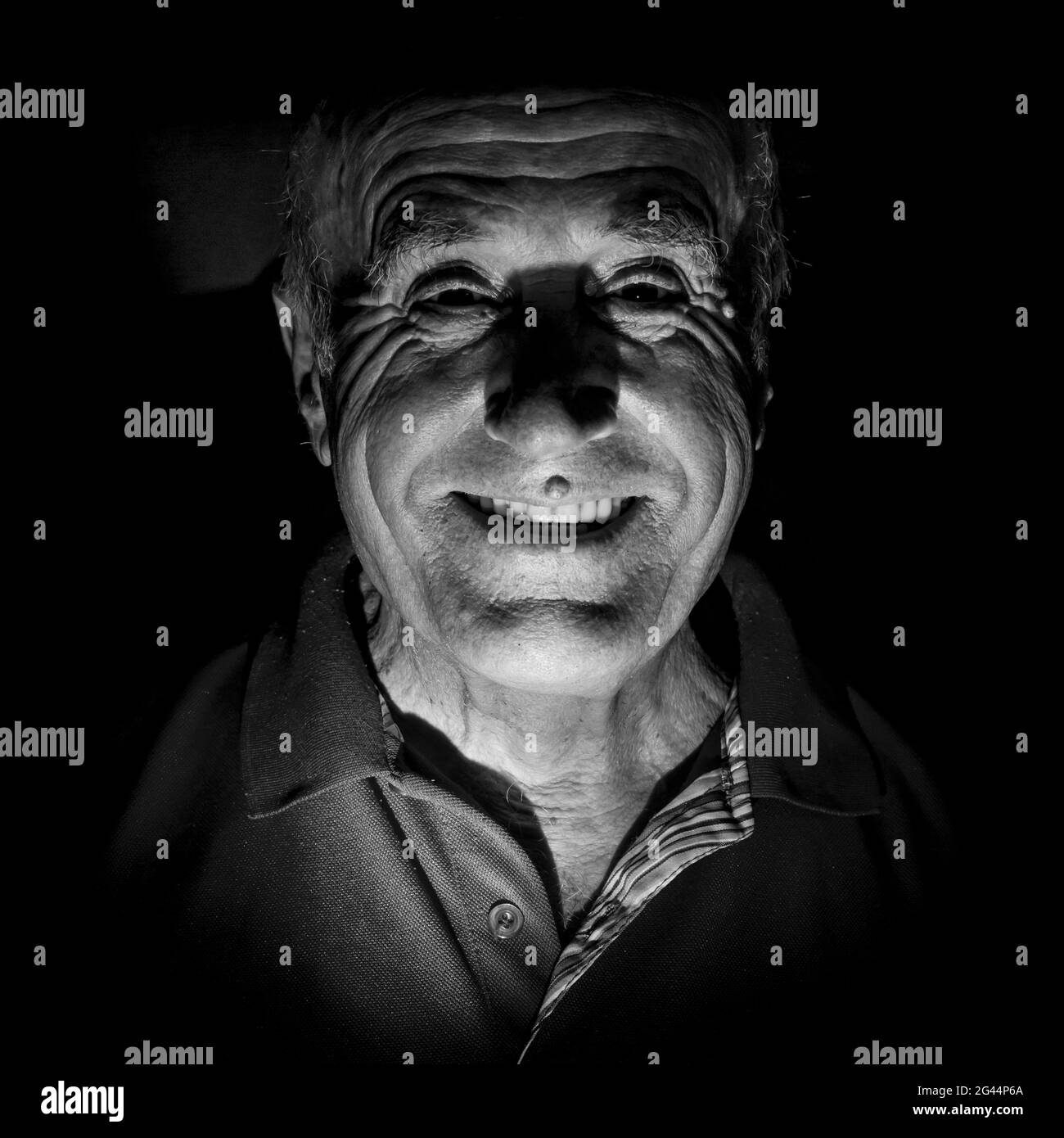 Portrait of smiling old caucasian man. Black and white shot, low-key lighting. Isolated on black. Stock Photo