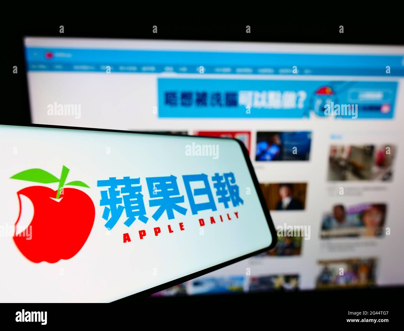 Smartphone with logo of Hong Kong newspaper Apple Daily on screen in front of business website. Focus on center-left of phone display. Stock Photo