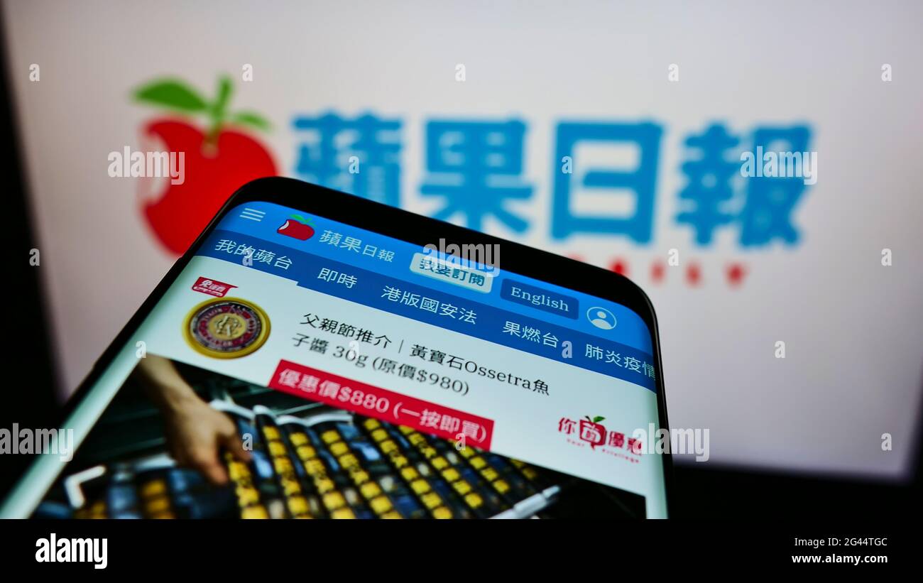 Mobile phone with website of Hong Kong newspaper Apple Daily on screen in front of business logo. Focus on top-left of phone display. Stock Photo