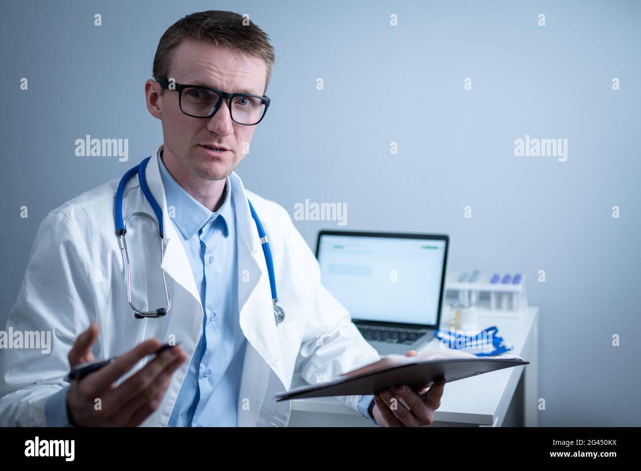 Young male doctor consults patient in hospital office, holding medical examinations in hands. General practitioner in white medi Stock Photo