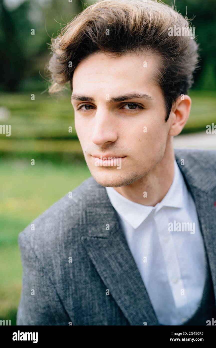 Portrait of young stylish groom in gray suit looking pensively at the camera Stock Photo