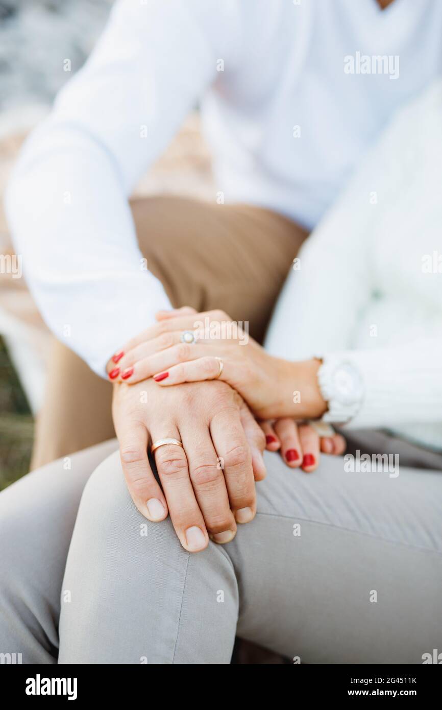 Woman's hand covered the man's hand. Man's hand lies on woman's leg. Close up Stock Photo