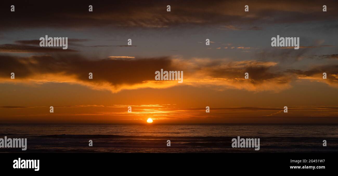 Moody orange sky at sunset above Pacific Ocean Stock Photo