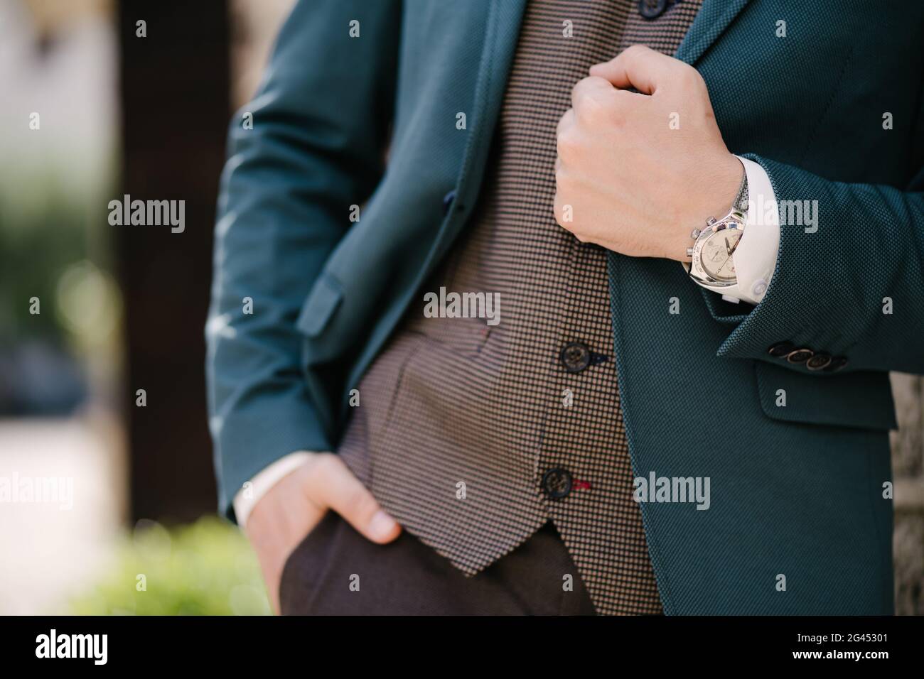 Groom holds his hand on the lapel of a blue jacket Stock Photo