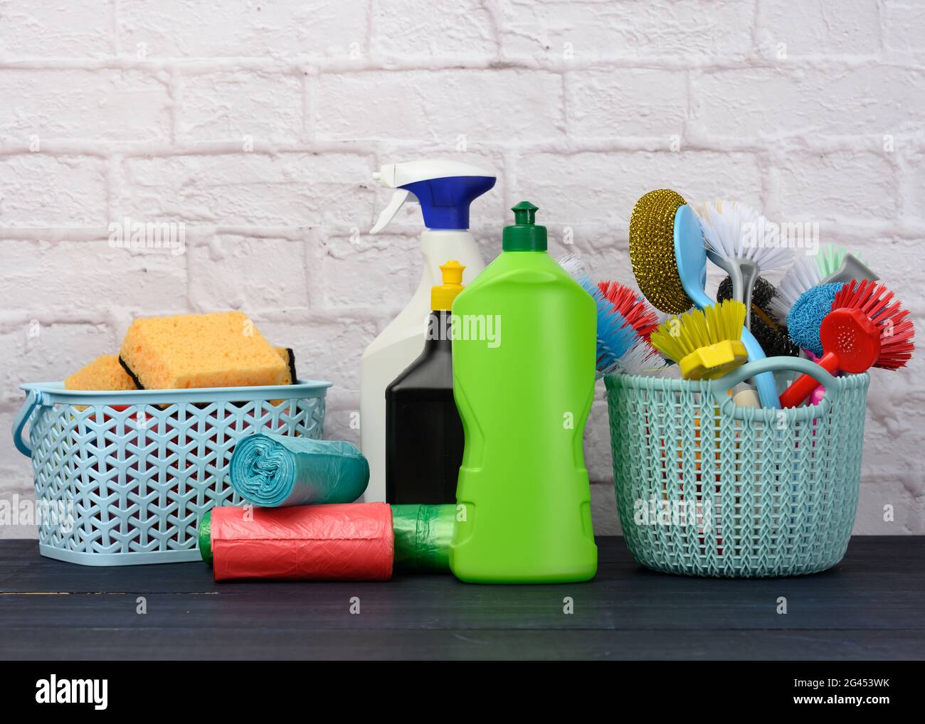 Sponges, plastic brushes and bottles of detergents on a blue wooden table. Household cleaning items Stock Photo