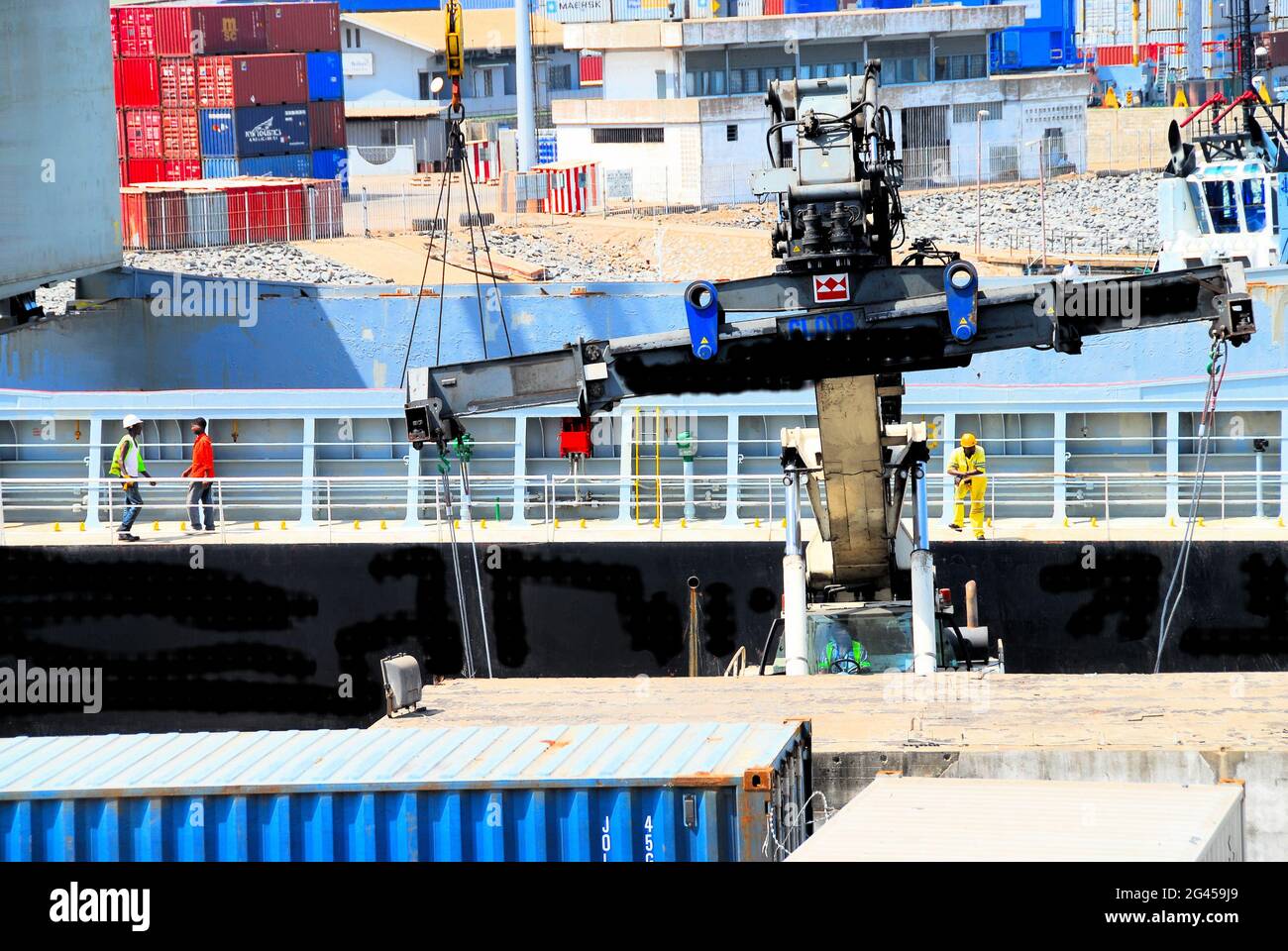 A photo of part of the tropical Port in Lomé, Togo, West Africa, with containers,  a crane. and shipyard workers. Stock Photo