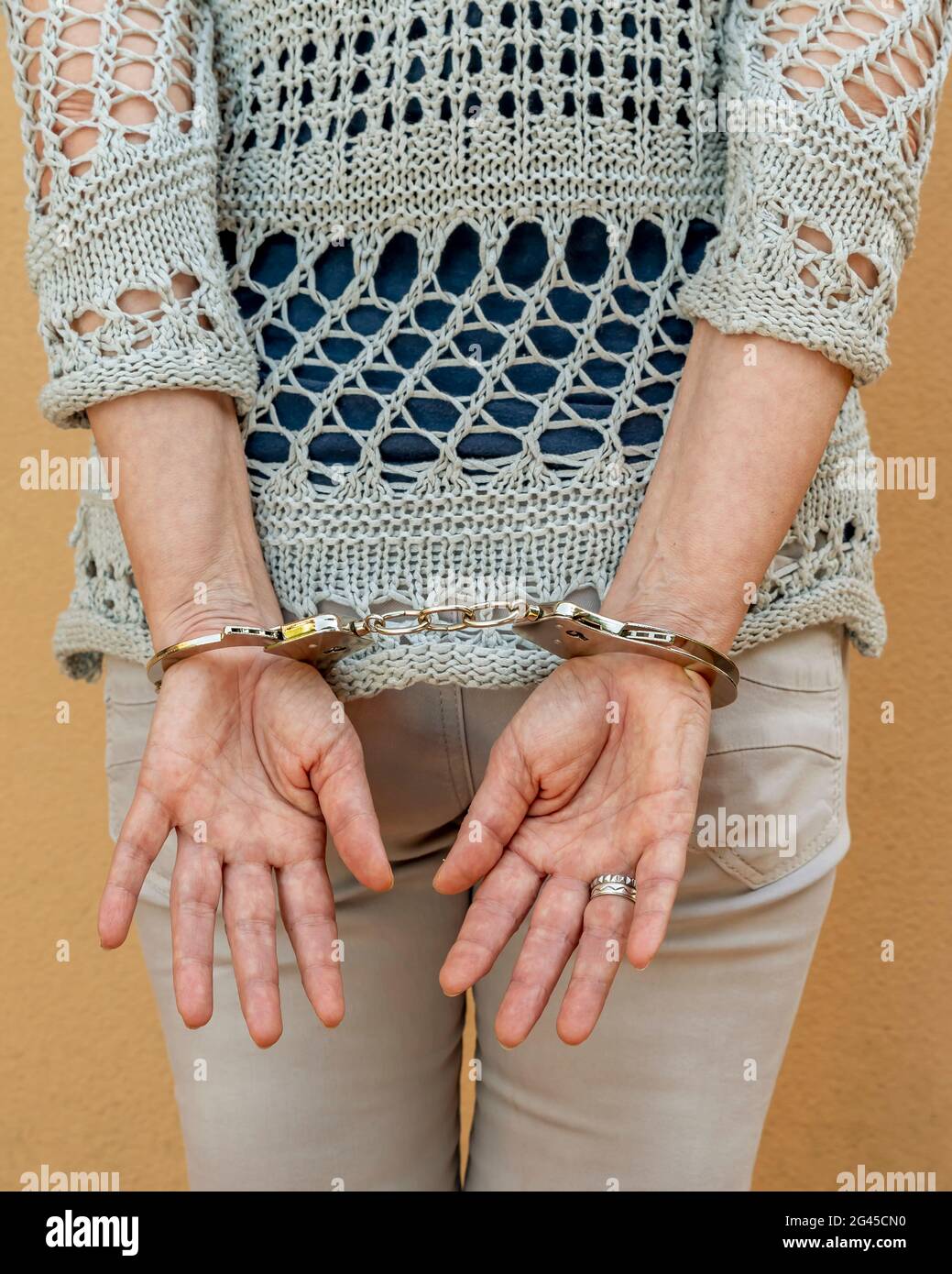 A woman is handcuffed while standing with her hands tied behind her back Stock Photo