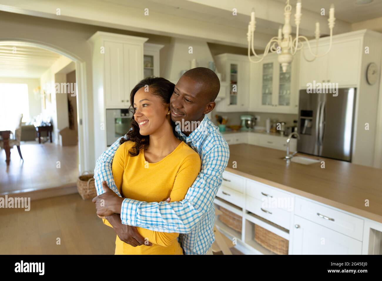 Happy couple hugging each other in their kitchen Stock Photo