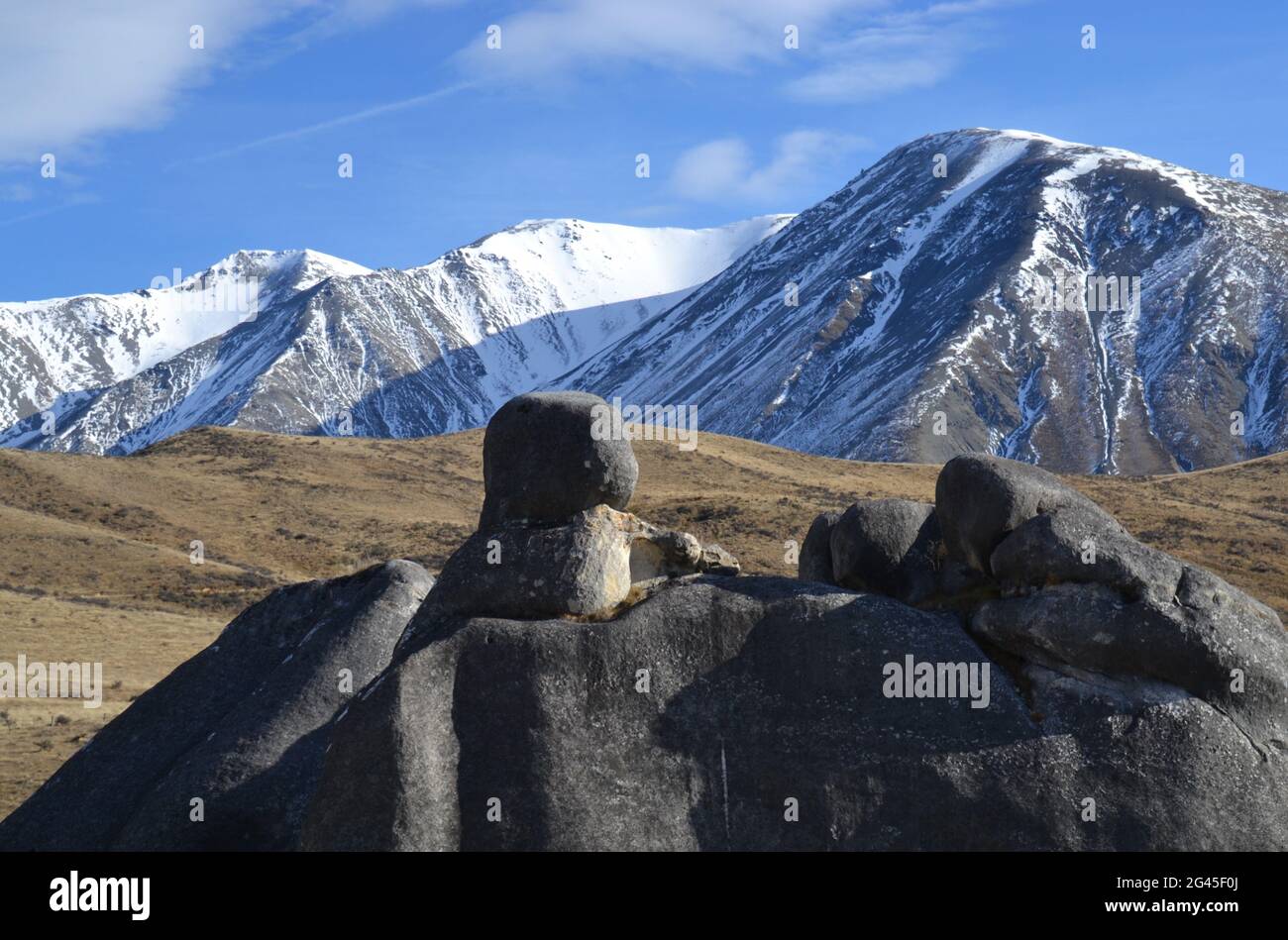 Geological historic site at Kura Tawhiti or Castle Hill Conservation site on New Zealand's South Island with large smooth boulders and snowy mountains Stock Photo