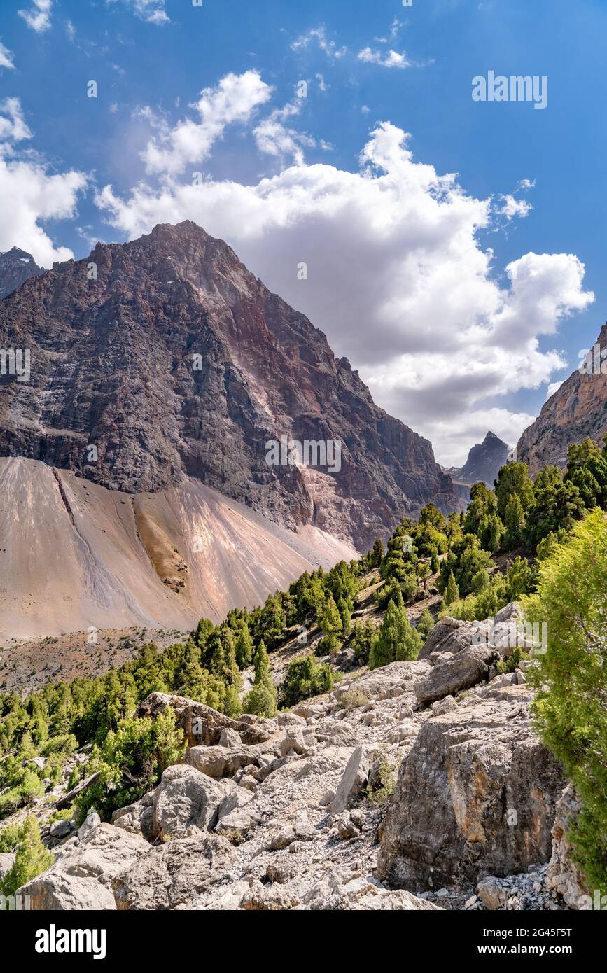 The beautiful mountain trekking road with clear blue sky and rocky hills and the view of Alaudin lake in Fann mountains in Tajik Stock Photo