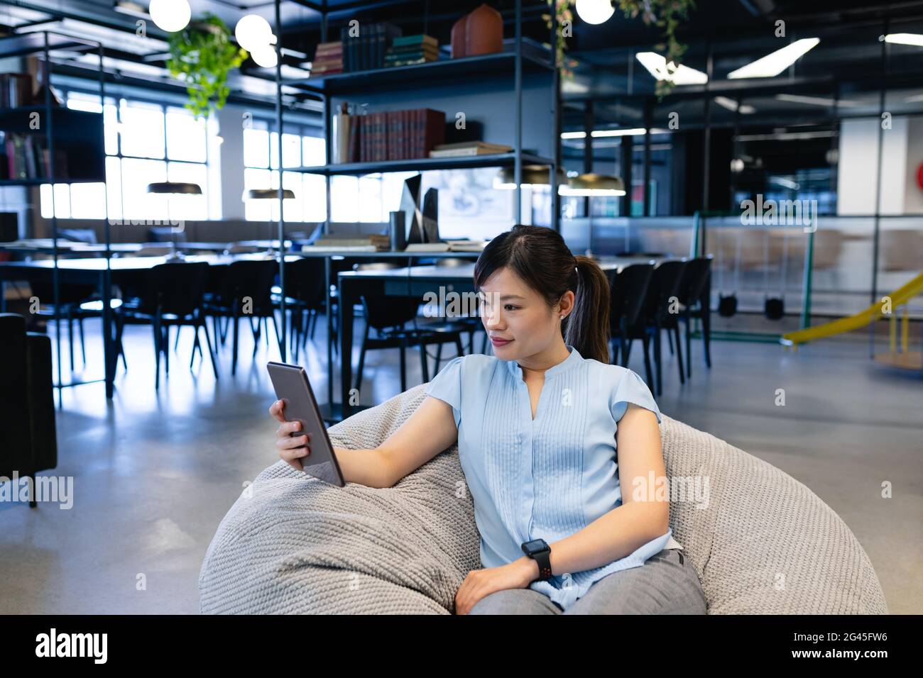 Asian woman sitting in a bean bag and holding a digital tablet Stock ...