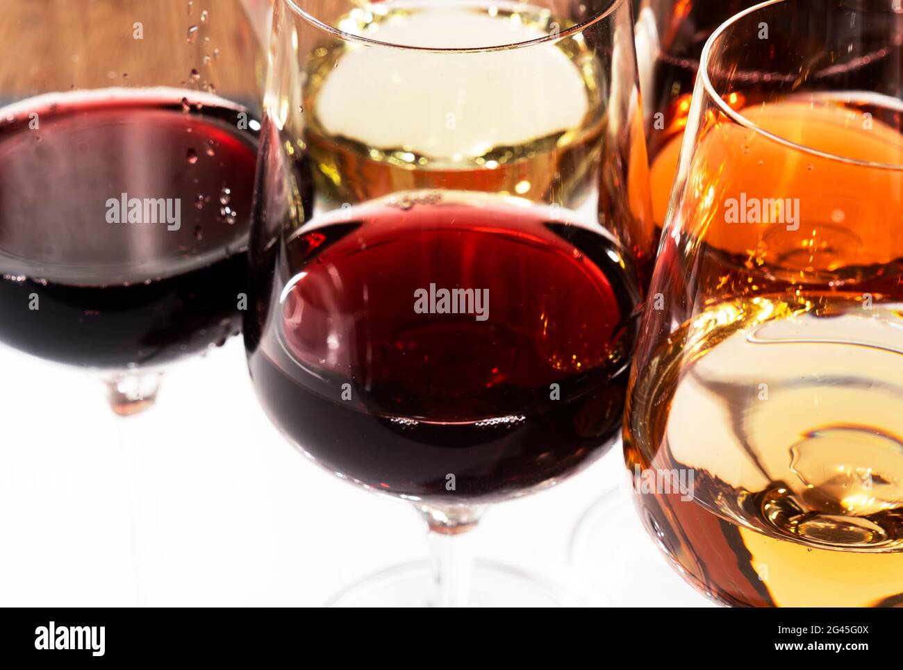 Wine tasting. Red wine shaking in glass on background with selection of red, white and rose