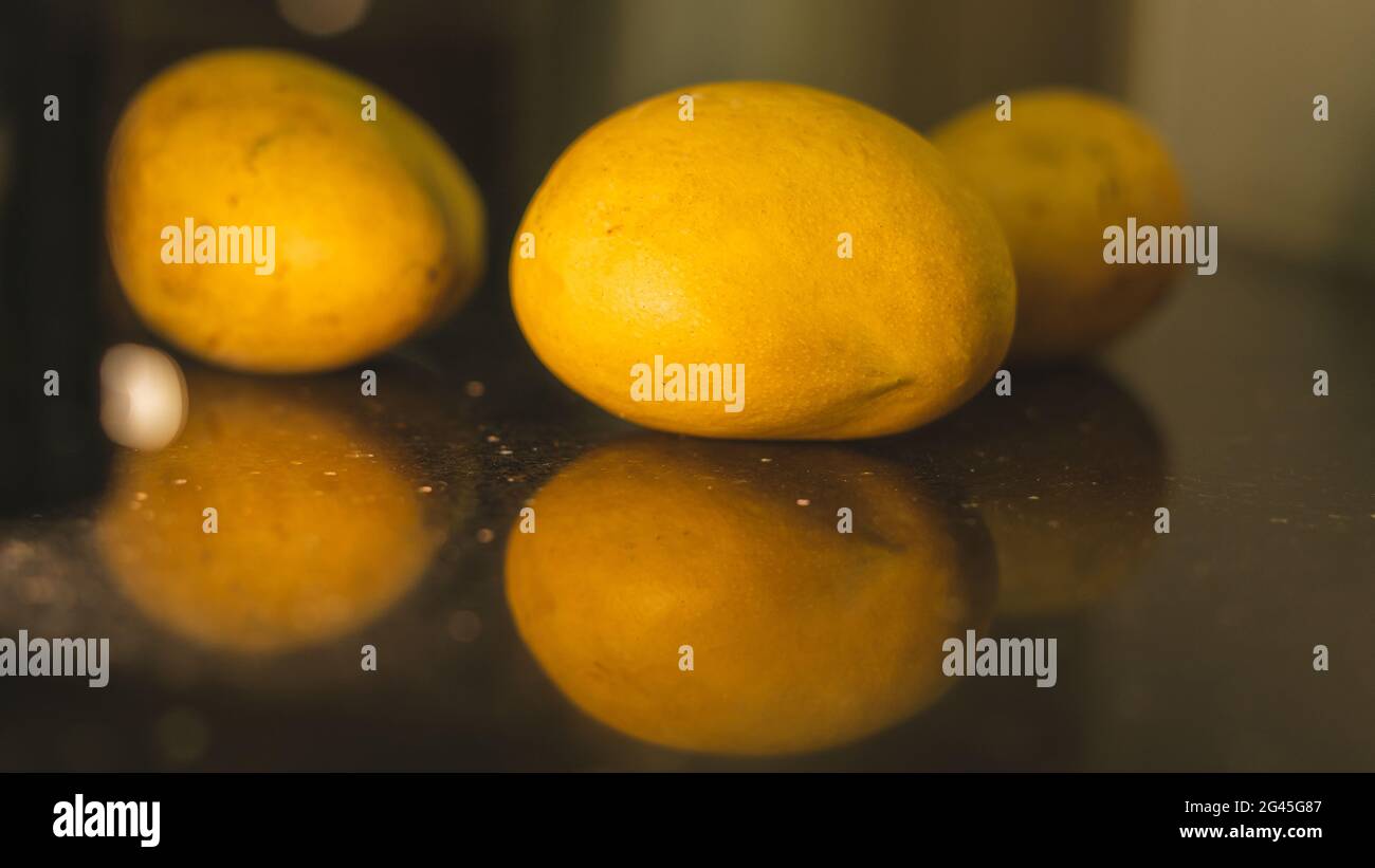 Selective focus of Alphonso mangoes on a black reflective background. Stock Photo